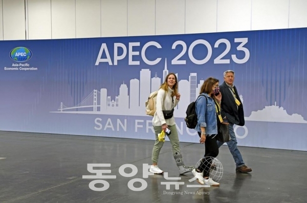 지난 12일 기자들이 미국 샌프란시스코 국제미디어센터(IMC)에서 아시아태평양경제협력체(APEC) 회의 개최 홍보 포스터를 지나고 있다.